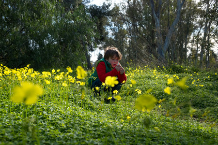 Five year old boy in a red jacket and green vest, as he walks through the country on a sunny winter afternoonの写真素材