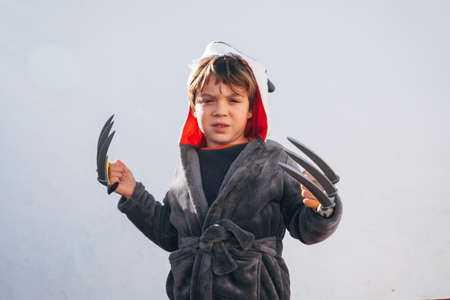 happy child with wolf claws, playing on the terrace of a house during the morning of a sunny winter dayの写真素材