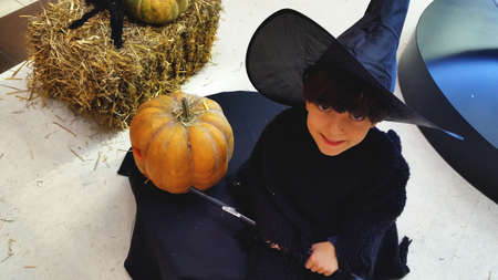 Little witch kid with big black hat and pumpkin. Halloween and Christmas costume.の写真素材