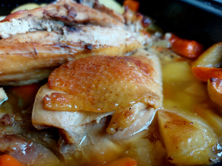 roast chicken with potatoes and carrots in a frying pan, close upの写真素材