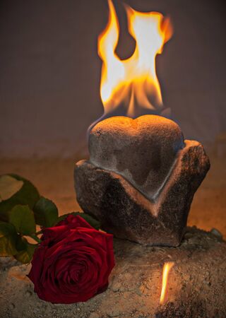 Heart carved in stone, flamen and roseの写真素材