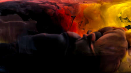Black, red & yellow acrylic paint creates abstract shapes in water