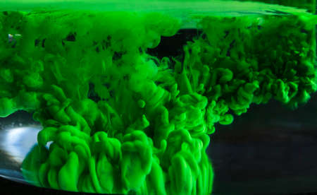 Green acrylic paint creates abstract shapes in waterの写真素材