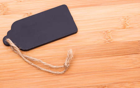 Image shows a black blank price tag on a wooden plateの写真素材