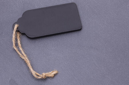 Image shows a black blank price tag on a grey slateの写真素材