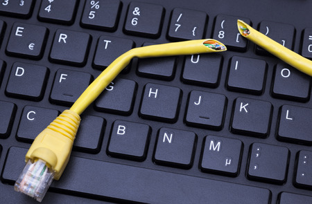 Image shows a computer keyboard and a broken LAN cable