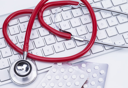 Image shows a red stethoscope at a computer keyboardの写真素材