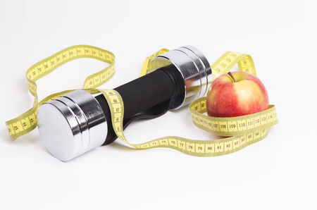  Image shows a a barbell a measure tape and a fresh appleの写真素材