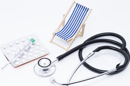 Image shows a deckchair sunglasses pills and a injectionの写真素材