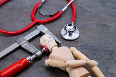 Image shows a wooden puppet with clamp and stethoscopeの写真素材