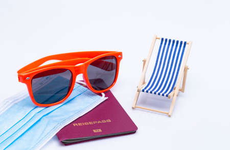 The photo shows sunglasses, passport, deck chair and a protective maskの写真素材