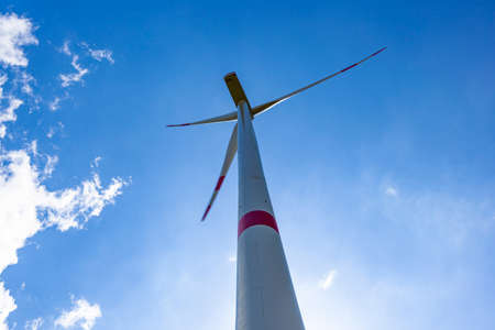 Wind turbine view with blades spinning around under a beautiful blue cloudy sky