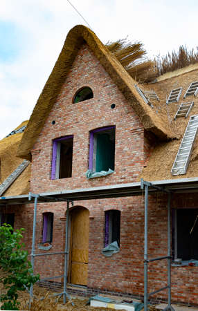 The photo shows a Frisian house under construction with thatched roofの写真素材
