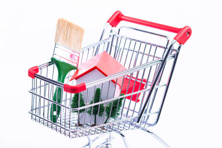 The photo shows a shopping cart in which there is a single-family houseの写真素材