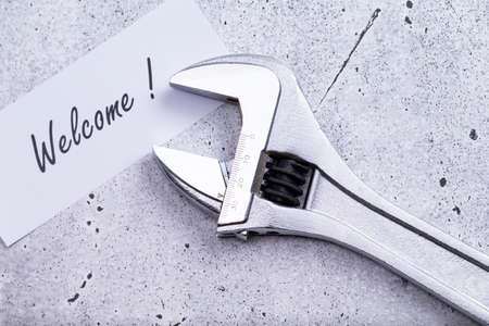 The photo shows a label with the words welcome with a wrench on a gray background