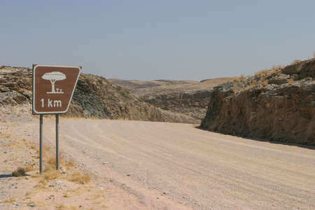 namibian gravel road with a sign for the next rest placeの写真素材