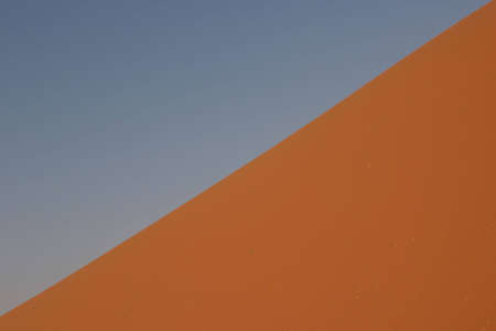 steep dune in the namibian desert dividing the image diagonal and leaving place for a blue sky の写真素材