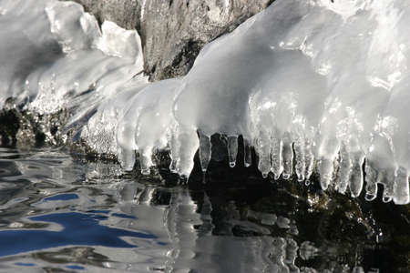 icy waterside with dripping icicles in bright sunlight