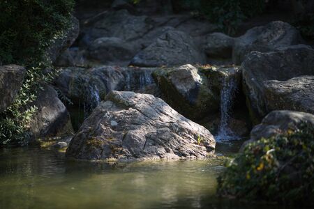 Rocks in a creek in front of a waterfall.の写真素材