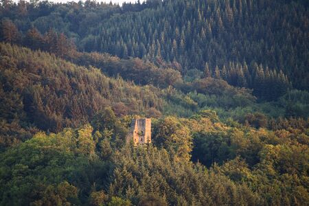 Ruined castle overlooks a dense forest with hills.の写真素材