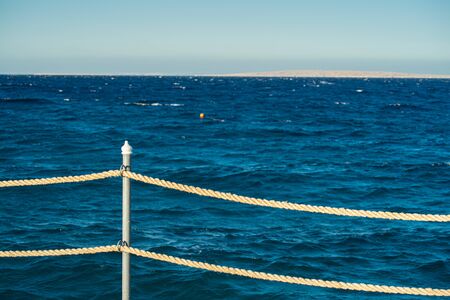Rope railing of a landing stage in the evening light. View over the Sea.の写真素材