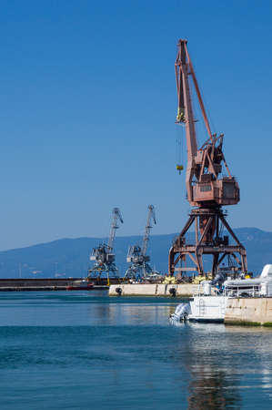 Harbor cranes on the quay wall of the port of Rijeka in the morning.の写真素材