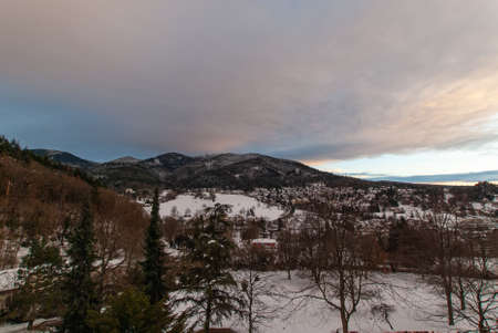 The clouds break up in the evening over the town of Badenweiler and forested hills in January.の写真素材