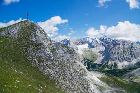 View of mountain peaks with summit cross in summer in the Alps.の写真素材