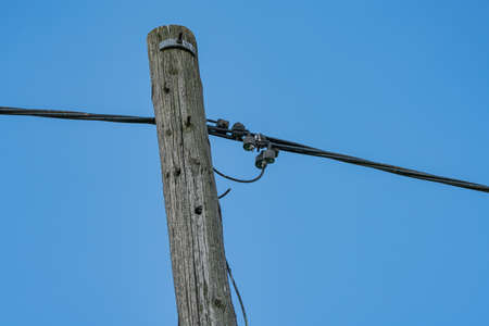 Connections on an old, wooden electricity pole against the sky.