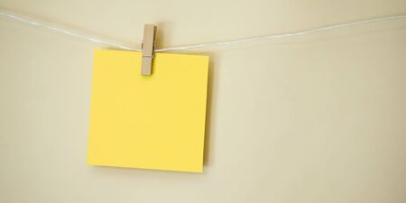 Colored Note Square Hanging 1. A bright yellow blank note square hanging on a white string line in...
