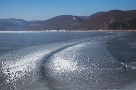 Cincis lake in winter. Hunedoara, Romania. Road on frozen lake in winter. Ice road on like. Road on ice lakeの写真素材