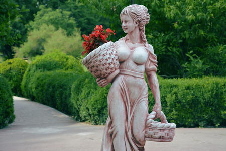 A statue with a basket of red flowers in handの写真素材