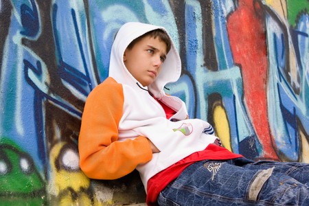 Retrospective teenager sitting near a graffiti wallの写真素材