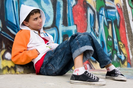 Teenager sitting near a graffiti wallの写真素材