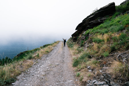 Hiker on a trail in the mountains with fog in the background