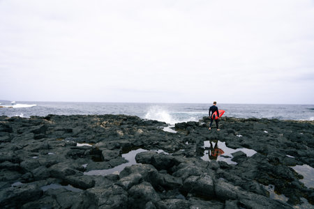 happy surfer on the coast with his red surfboardの写真素材
