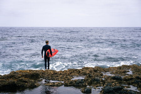 happy surfer on the coast with his red surfboardの写真素材