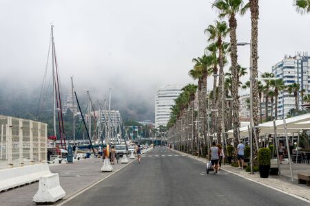 Malaga, Spain - June 24: People walk past a fog and mist covered hill in the city of Malaga, Spain, Europe on a foggy summer morningのeditorial素材