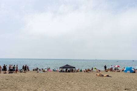 Malaga, Spain - June 24: People basking in the sun at Malagueta beach in Malaga, Spain, Europe on a cloudy dayのeditorial素材