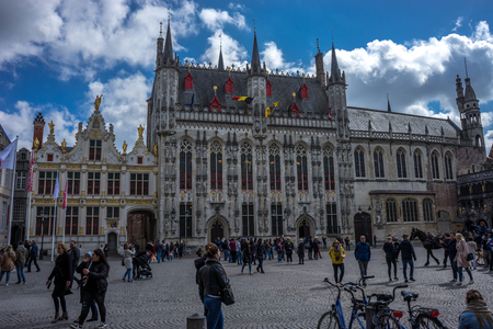 Brugge, Belgium - April 17 :  Toursists walking at the Burg Square in Bruges, Belgium, Europe on a bright sunny day with blue skyのeditorial素材