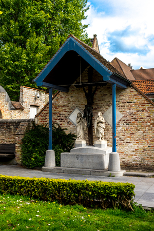 Two white statues below a slanting roof in the city of Brugge, Belgium, Europe on a bright summer dayの写真素材