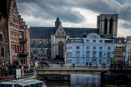 Ghent Belgium - April 15 : Toursists walk across the bridge near the Saint Michael's Church in Ghent, Belgium, Europeのeditorial素材