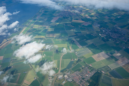 Farms in Holland, Netherlands with canal viewed from plane in sky, Europe with clouds