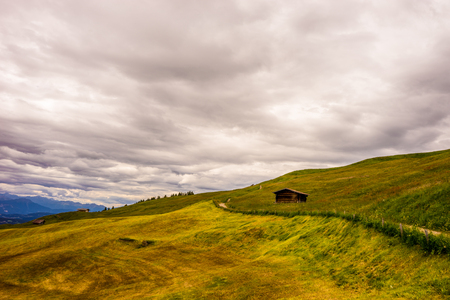 Italy, Alpe di Siusi, Seiser Alm with Sassolungo Langkofel Dolomite, an old barn in a fieldの写真素材