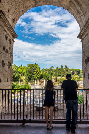 Rome, Italy - 23 June 2018: Ruins of the roman forum viewed through the gated arch of the passage at the entrance of the Roman Colosseum (Coliseum, Colosseo), also known as the Flavian Amphitheatre. Famous world landmark. Scenic urban landscape.のeditorial素材