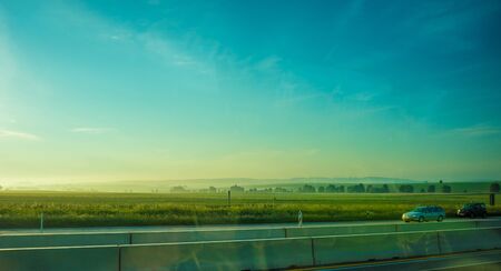 Germany, Frankfurt, Sunrise, Outkirts, a large green field with trees in the backgroundの写真素材