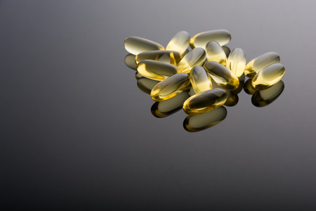 Omega 3 cod liver oil gel capsules on shiny background