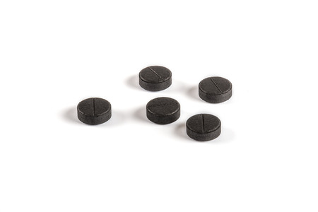 Black activated carbon tablets on white backgroundの写真素材