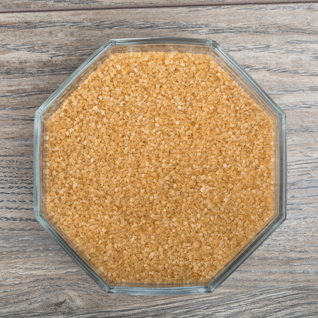 Bowl with brown granulated sugar on wooden tableの写真素材