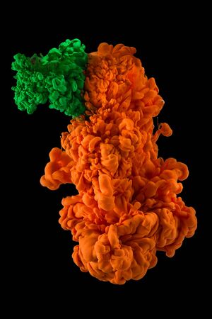 Plumes of ink in water blending together. Green and orangeの写真素材